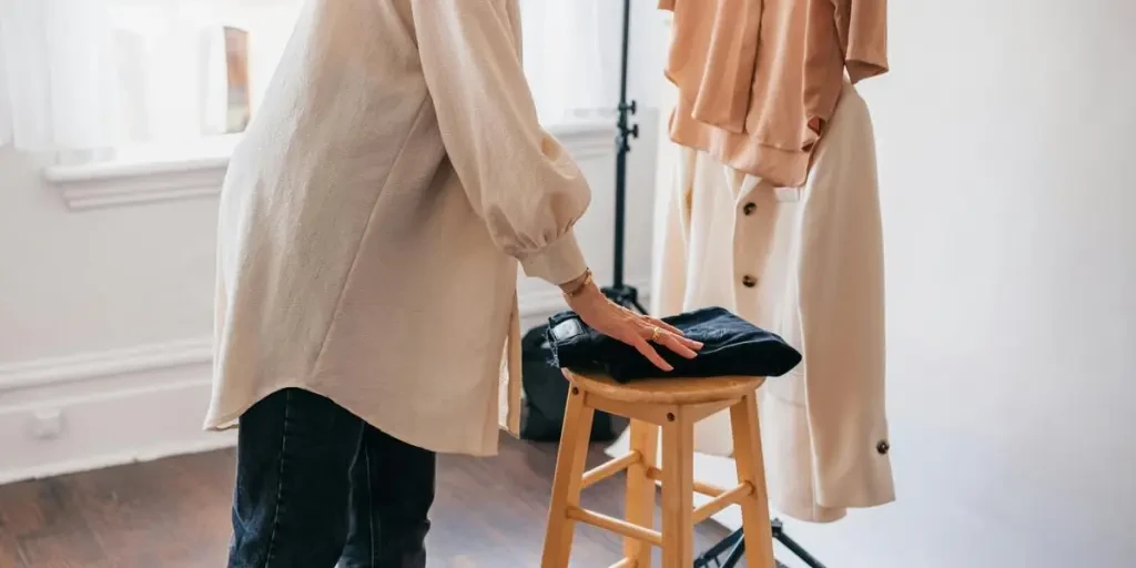 A person arranging clothes indoors, showcasing fashion and interior design elements