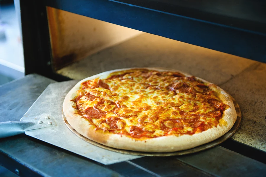 A pizza with cheese baking in an electric oven