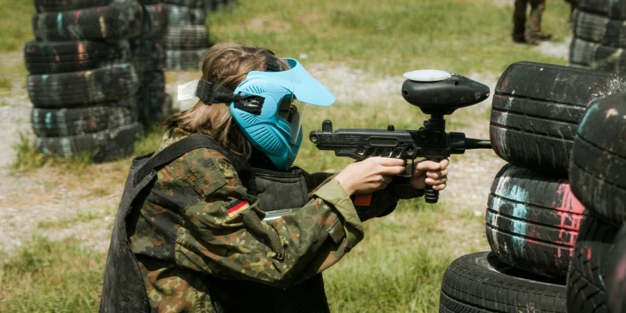 A player in camouflage and protective gear participates in a paintball game