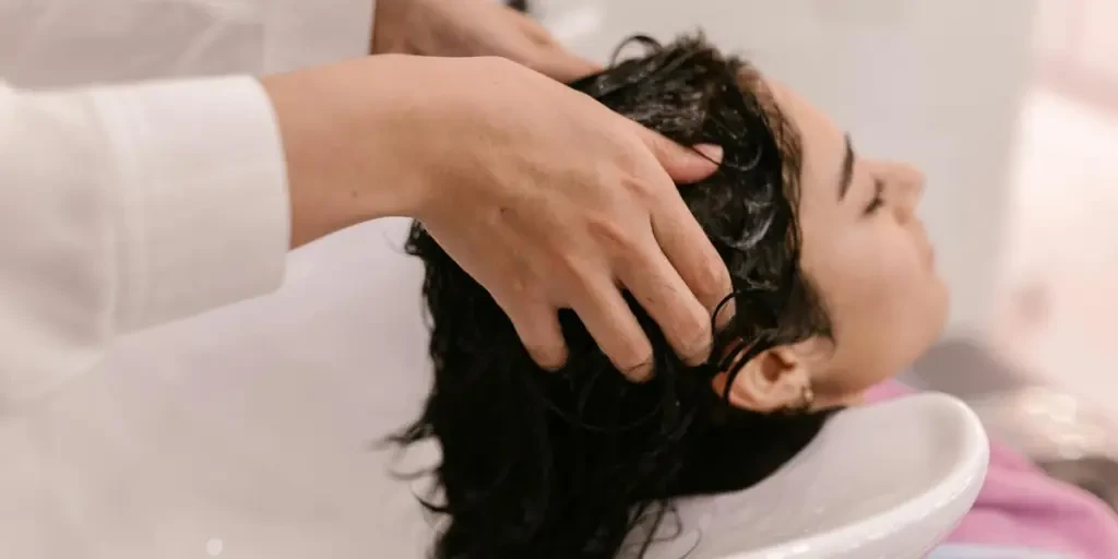 A woman enjoys a relaxing hair wash at a salon. Captured in a cozy indoor setting