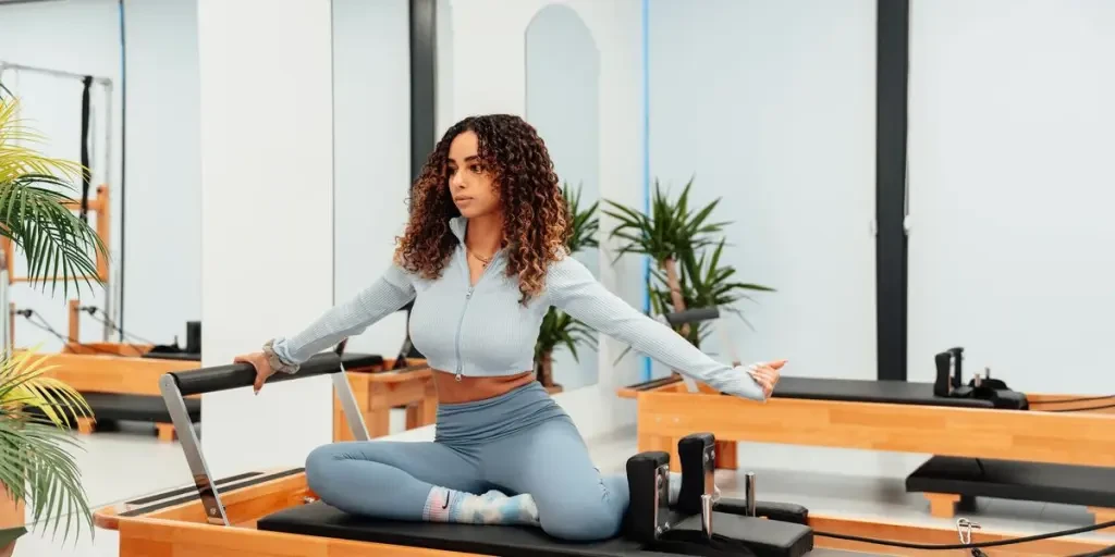 A woman performs pilates on a reformer machine in a modern studio, promoting fitness and balance