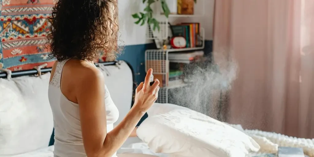 A woman sits on her bed, spraying a fragrant mist to refresh the room by Photo