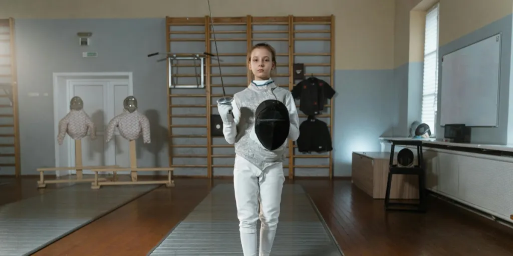 A young female fencer trains indoors, showcasing skill and fencing gear