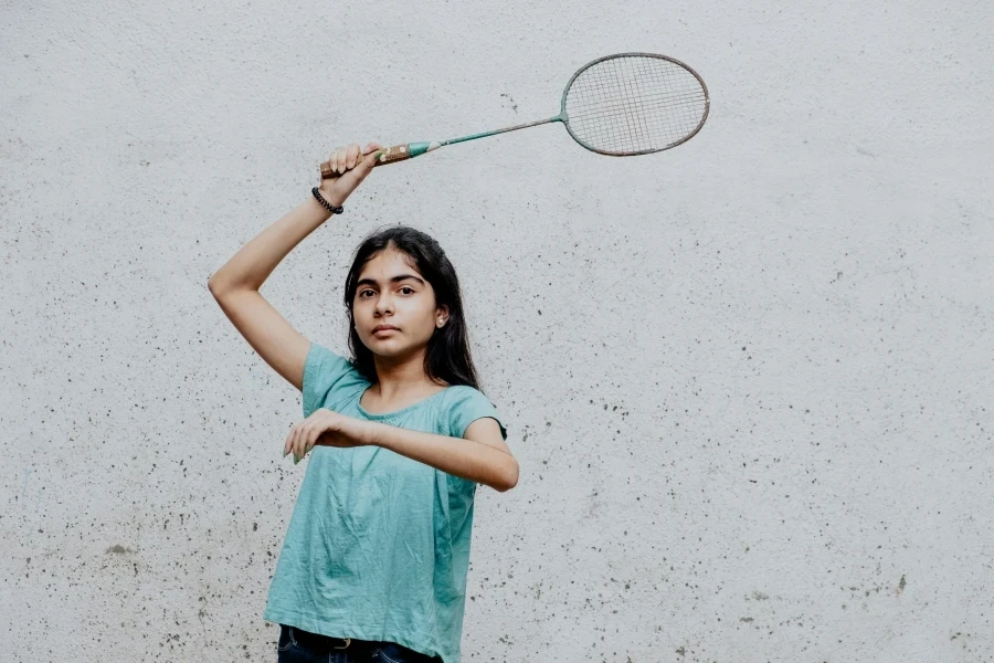 A young girl deeply focused as she plays badminton, showcasing skill and concentration