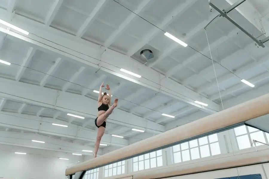 A young gymnast gracefully executing a routine on the balance beam in an indoor gym