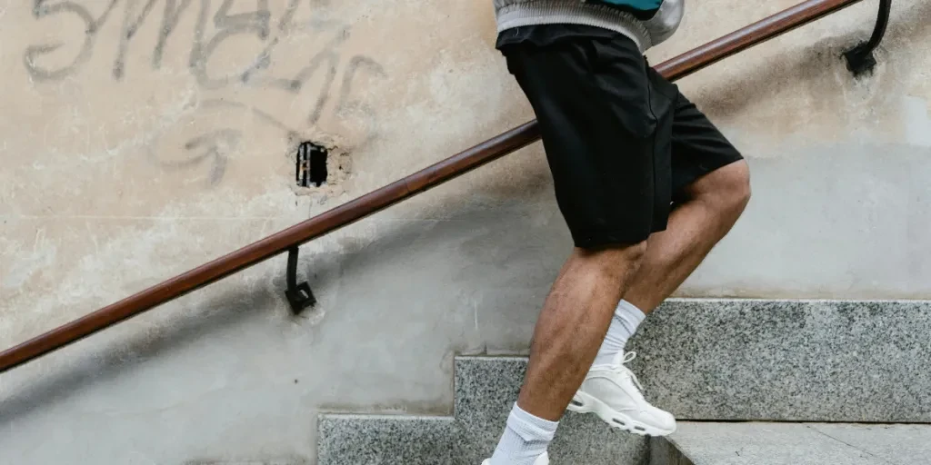 Adult male in athletic attire climbing stairs outdoors, emphasizing fitness and energy by MART PRODUCTION