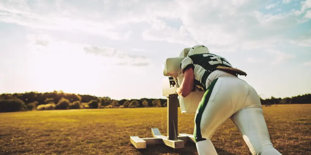 American football player doing tackling drills during practice