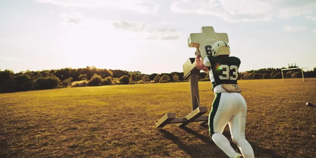 American football player doing tackling drills on a football field