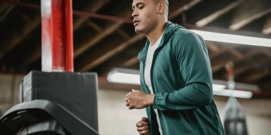 An athletic man in activewear running on a treadmill indoors, focused on fitness and health