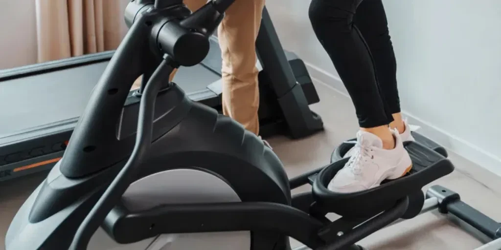 An elderly lady is using a step machine with the assistance of a personal trainer or physiotherapist in a clinic gym