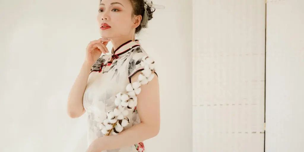 An elegant woman in a floral qipao dress poses indoors with refined sophistication