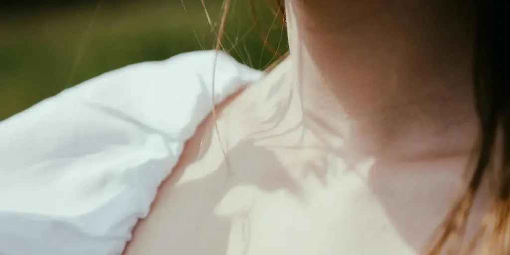 Artistic close-up of a womans neckline in a white dress captured outdoors in daylight