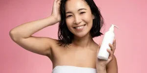 Asian woman holding hair conditioner before applying