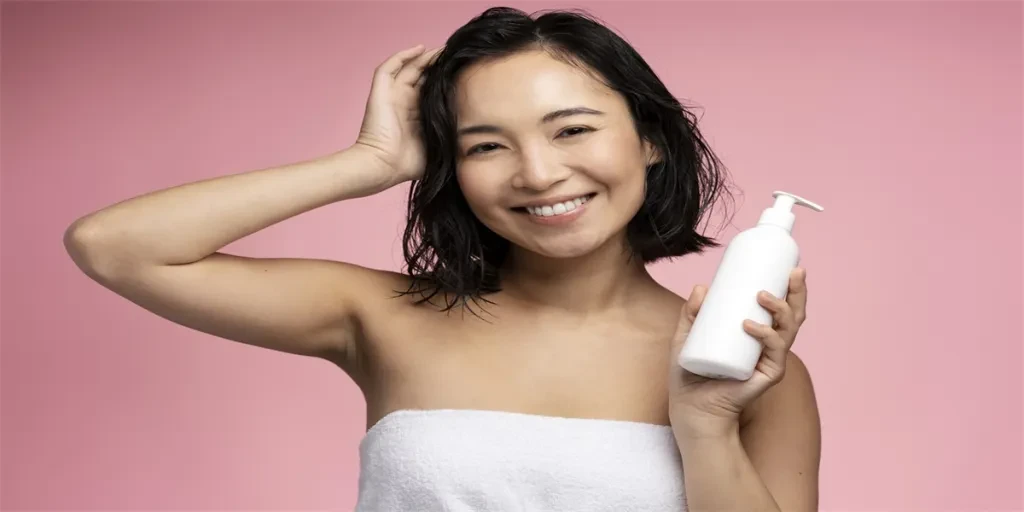 Asian woman holding hair conditioner before applying