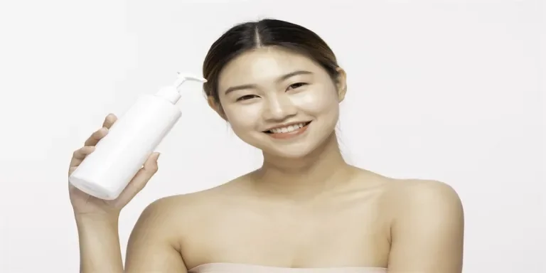 Attractive Asian young woman smile with white teeth holding white Lotion bottle feeling so happy and cheerful with healthy Clean and Fresh skin