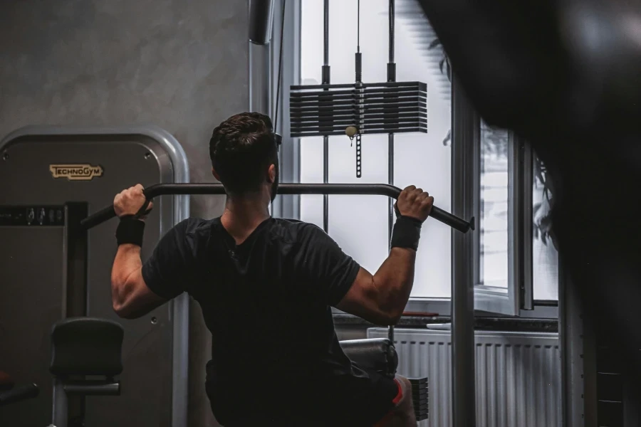 Back view of a man exercising with lat pulldown machine in the gym