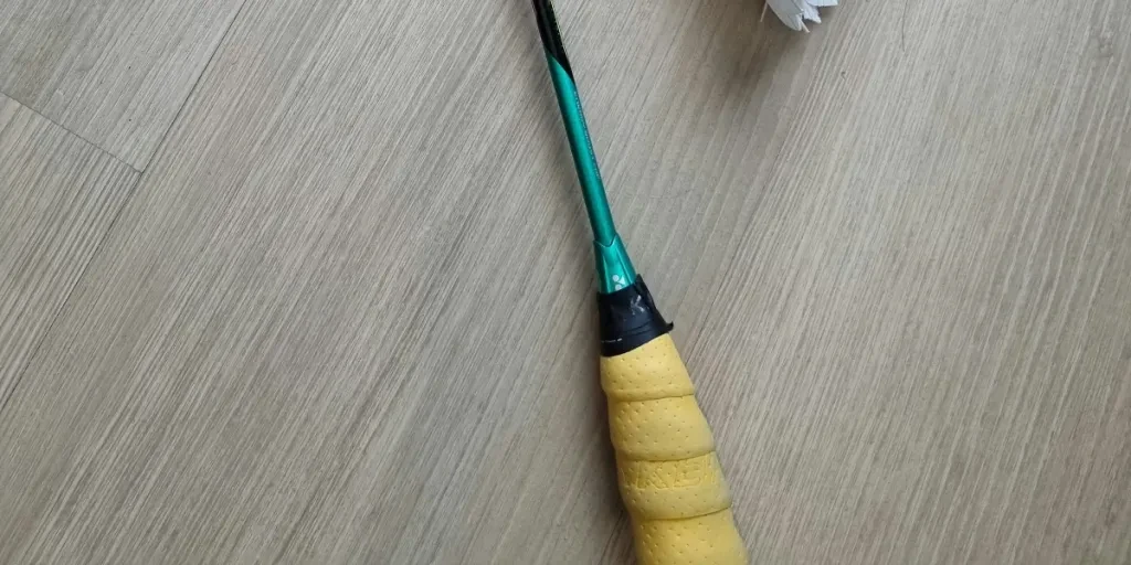 Badminton racket with three shuttlecocks on a wooden floor, perfect for sport and recreation concepts