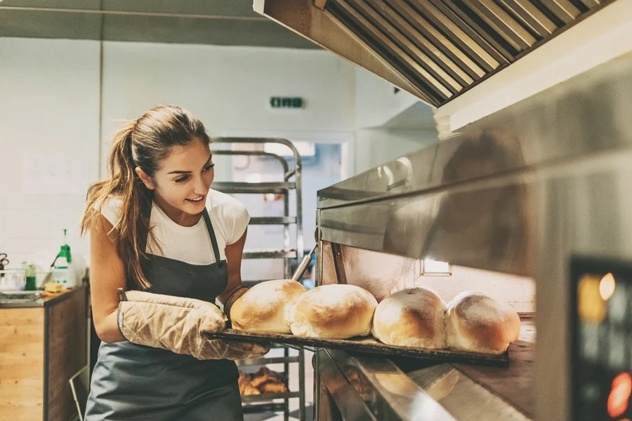 Baker pulling out a tray of freshly baked bread