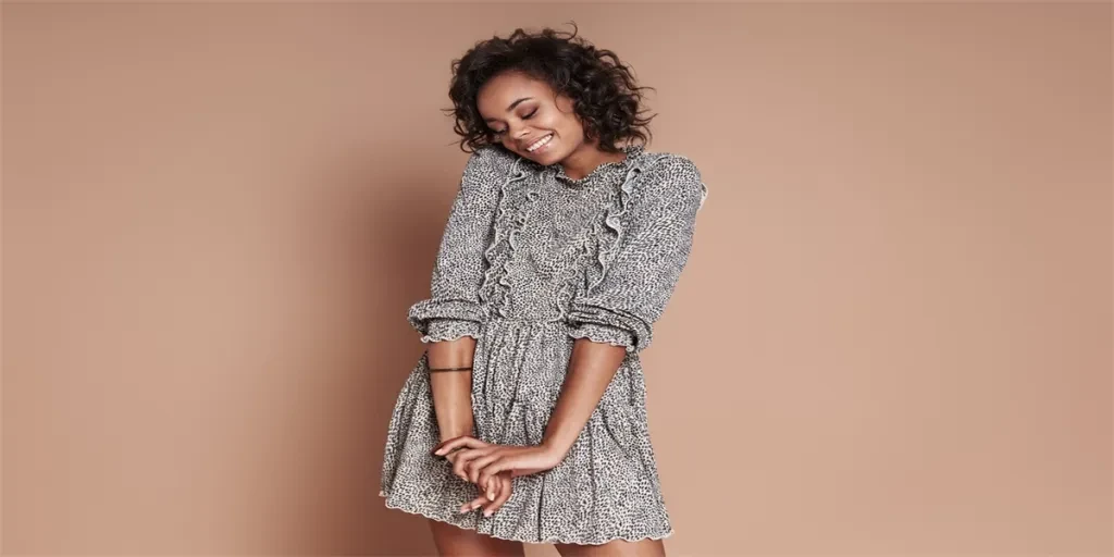 Beautiful young African woman smiling while standing against brown background