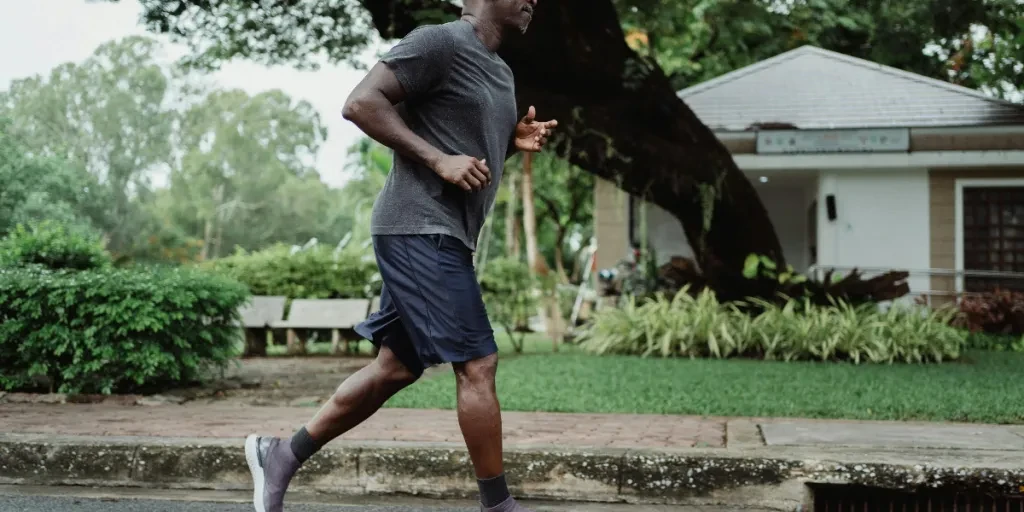 Black man jogging in park, promoting fitness and wellbeing by Ketut Subiyanto