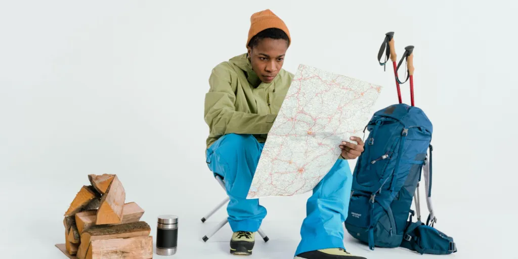 Black man preparing for winter hiking adventure with map and gear setup