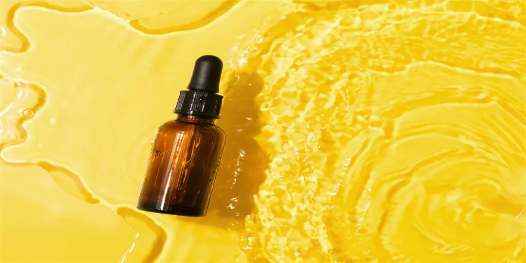 Bottle serum, oil cosmetic in clean transparent water with sunlight on yellow background