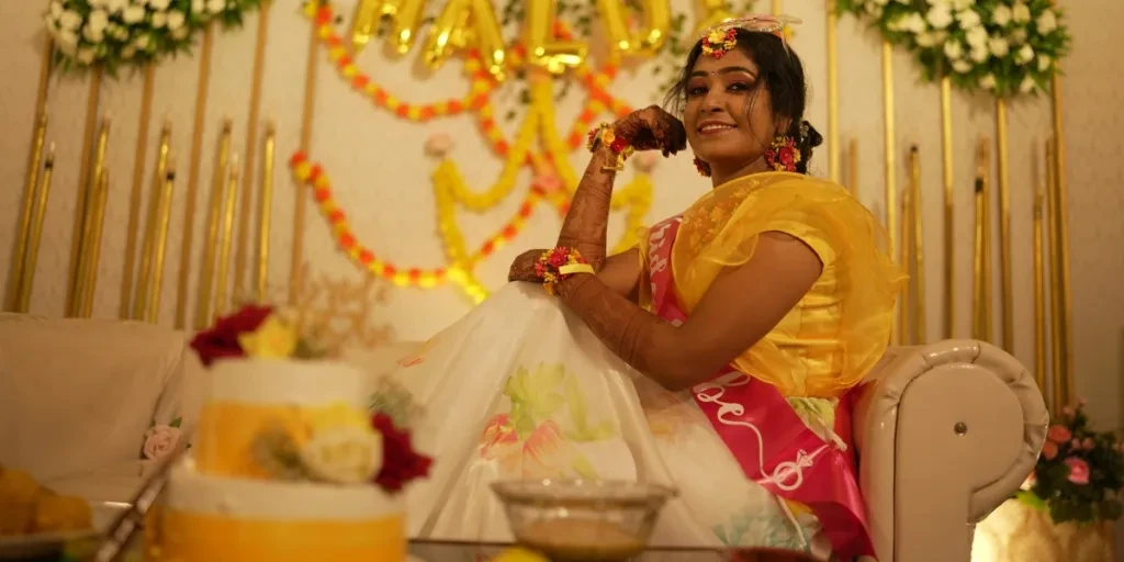 Bright and joyful haldi ceremony featuring a smiling bride in traditional Indian attire with floral decorations