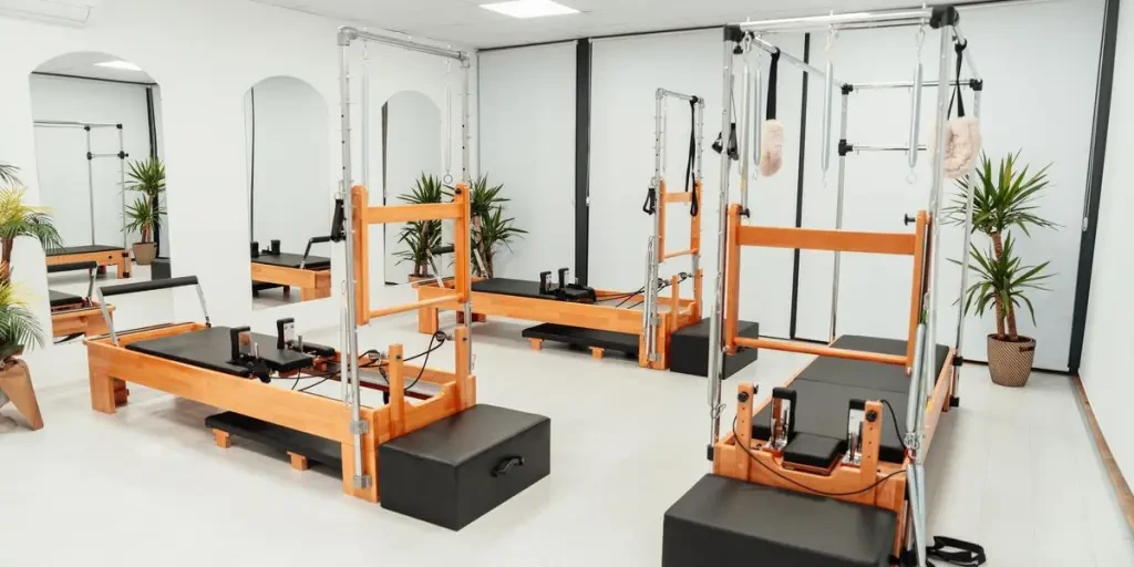 Bright, spacious Pilates studio featuring wooden pilates towers and lush plants