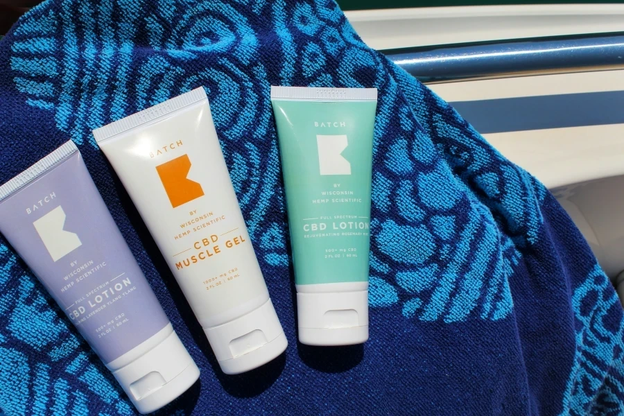 CBD lotions spread out on a beach towel on a boat in the lake by BATCH