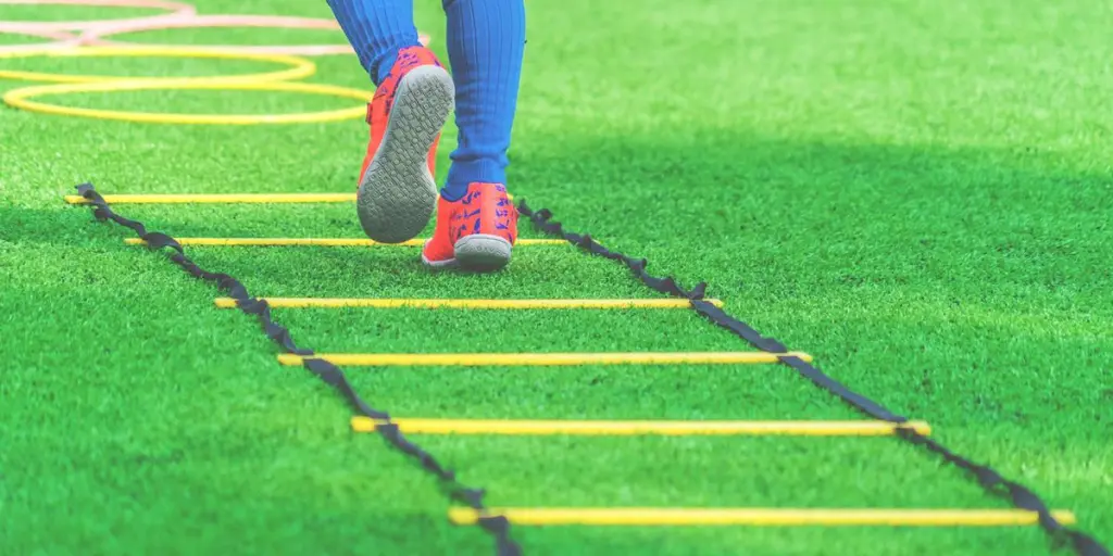 Child feet with soccer boots training on agility speed ladder in soccer training.