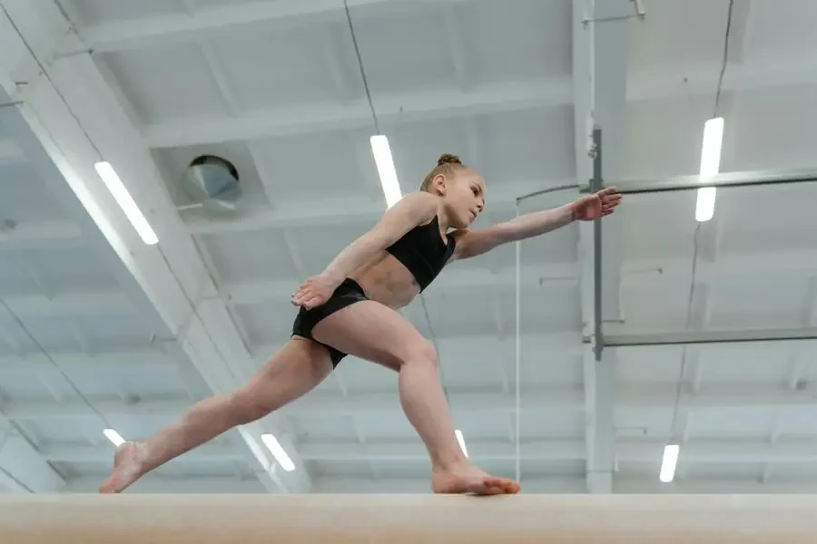 Child gymnast performing balancing act on beam in a gymnasium setting