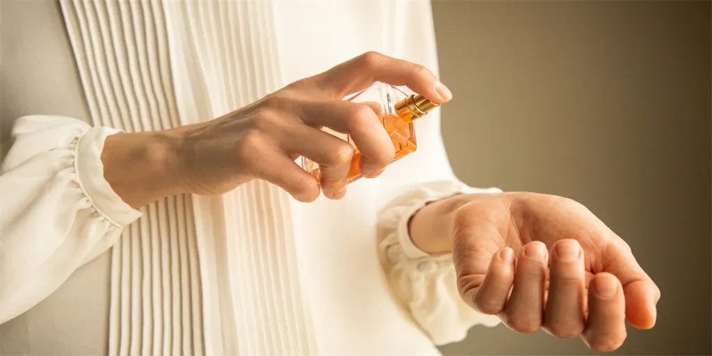 Classy look of young woman applying and testing perfume on her wrist