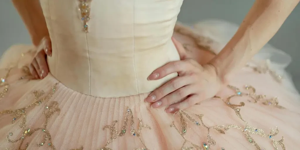 Close-up of a ballerinas detailed pink tutu with delicate embroidery, hands on hips