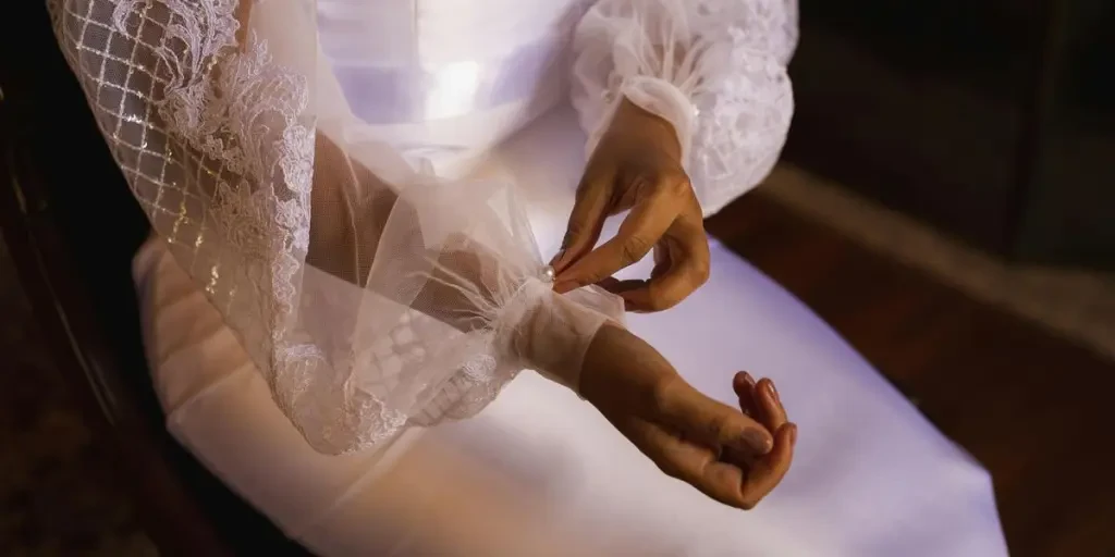 Close-up of a bride adjusting the lace sleeve of her elegant wedding dress, showcasing delicate details