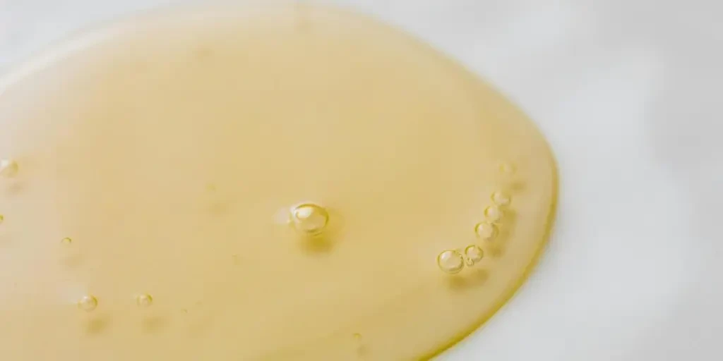 Close-up of a golden liquid with bubbles on a white surface, showcasing beauty and purity