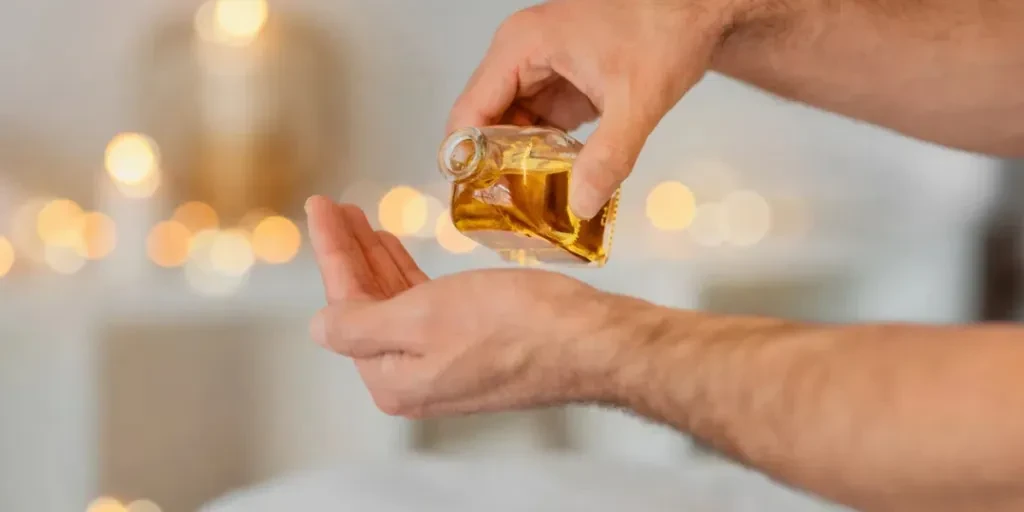 Close-up of a man masseur hands being prepared with essential oil for a restorative massage session