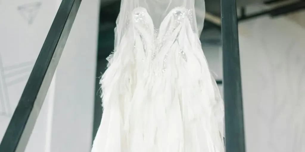 Close-up of a white bridal dress hanging on a yellow hanger indoors