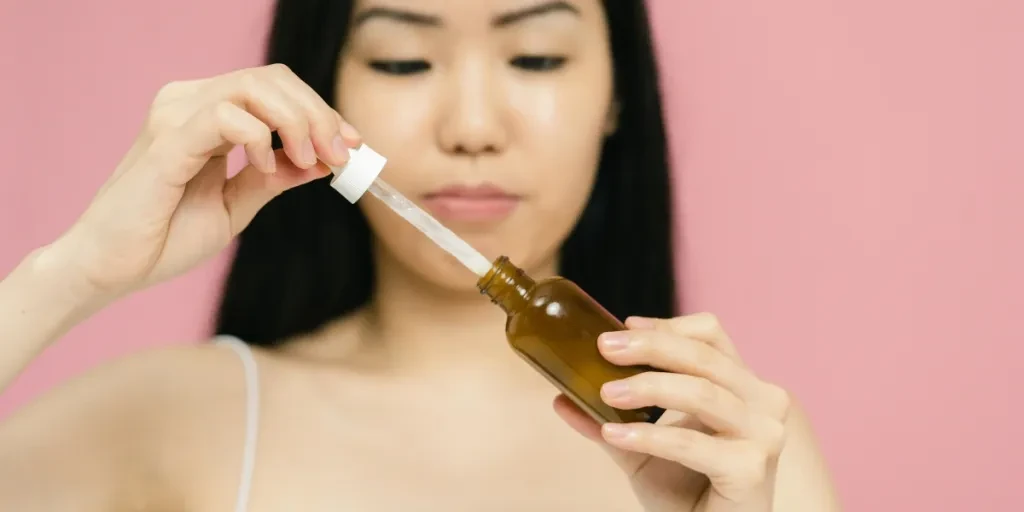 Close-up of a Close-up of a woman holding a serum bottle with a dropper, focusing on skincare