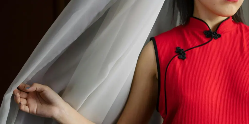 Close-up of an elegant woman in a red qipao dress and red lipstick, indoors