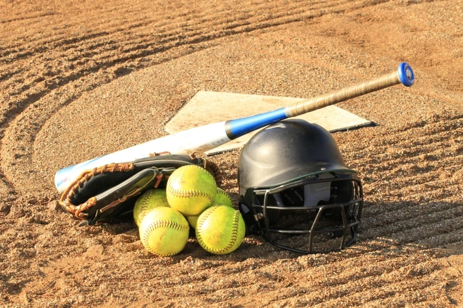 Close-up of baseball and softball gear on a dirt field, ready for a game