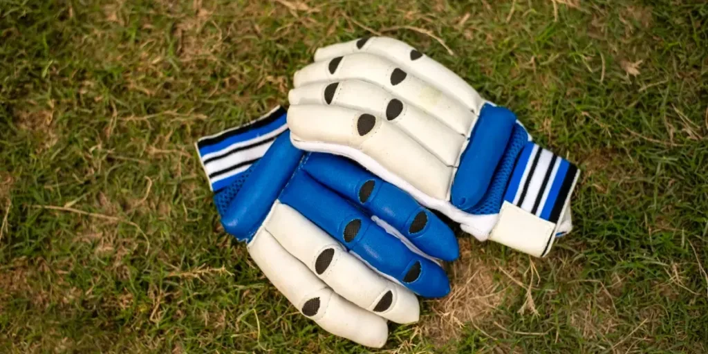 Close-up of cricket gloves on green grass pitch