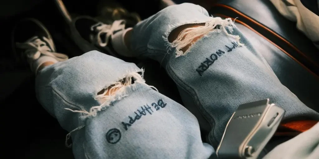 Close-up of legs in ripped jeans and sneakers, showing casual fashion style and focus on safety with seatbelt