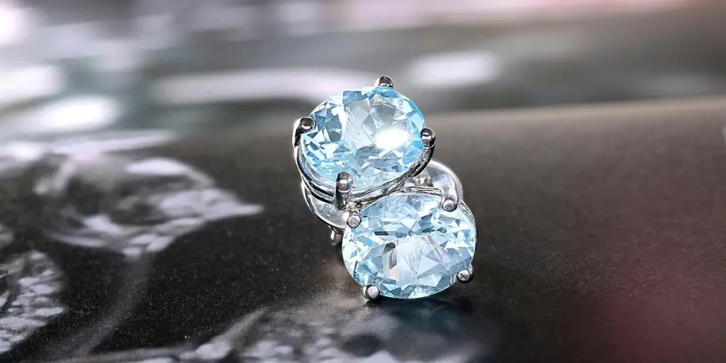 Close-up of luxurious blue topaz earrings set in white gold, showcasing their dazzling oval cut and brilliance