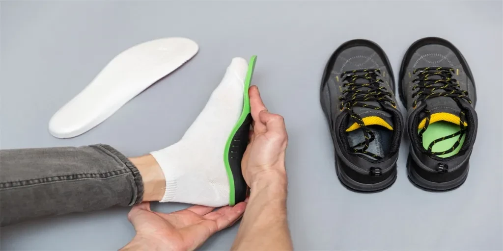 Close up of man hands fitting orthopedic insoles on a gray background