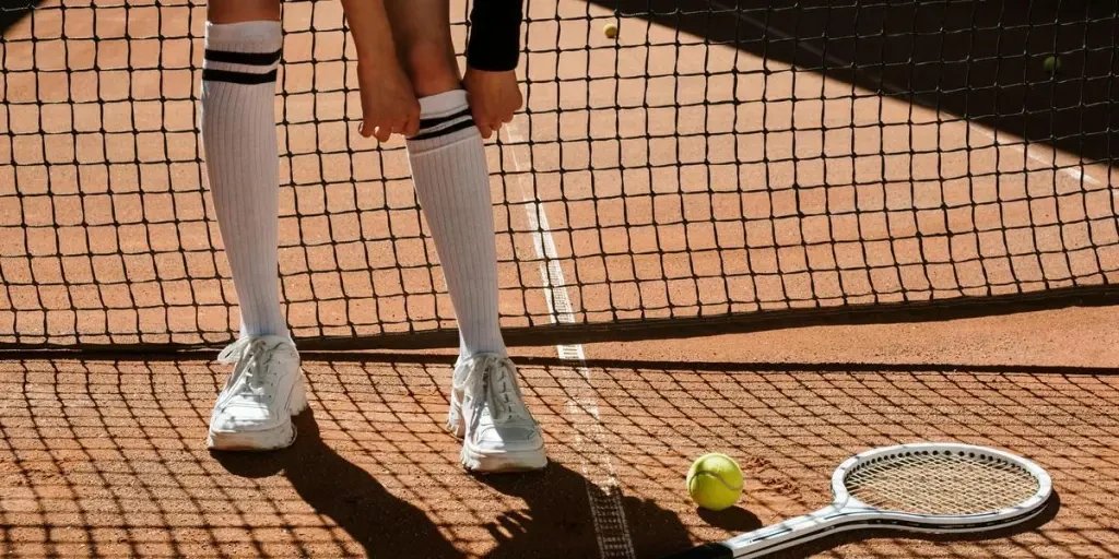 Close-up of tennis players feet on a clay court with racket and ball