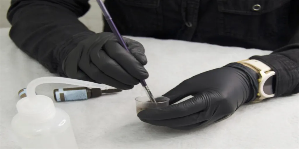 Close-up of the eyebrow master's hands stirring the eyebrow dye