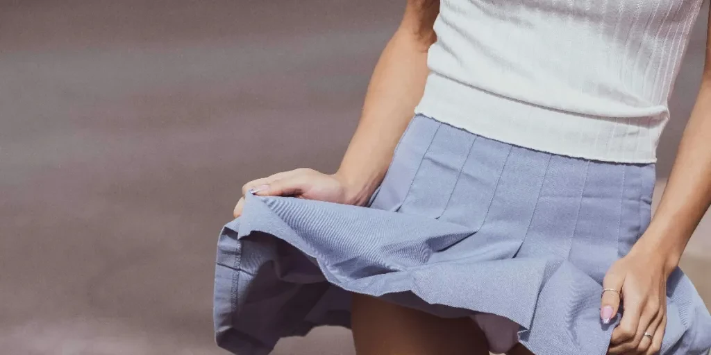 Close-up of woman in skirt holding skateboard outdoors