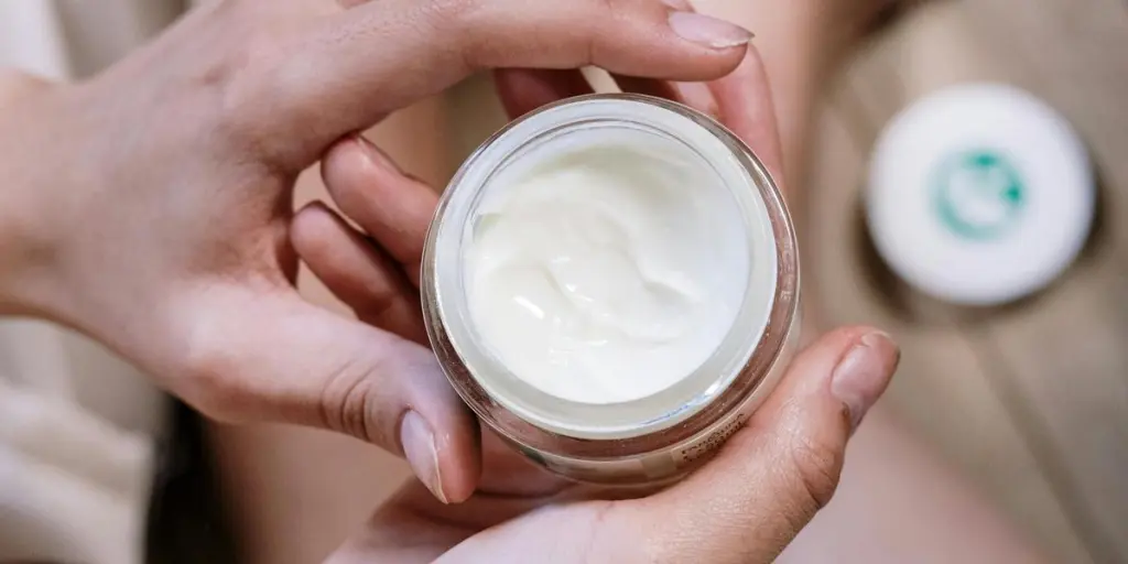 Close-up of womans hands applying skincare cream during morning routine indoors