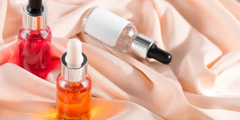 Close-up serum essence in glass bottle on beige silk background