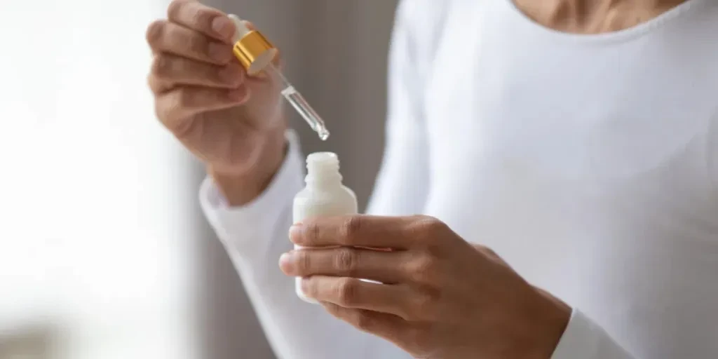 Close up young woman holding bottle with pipette